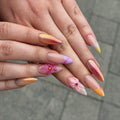 Hand with handmade iridescent sunset chrome pink 3D floral press-on nails, almond shape