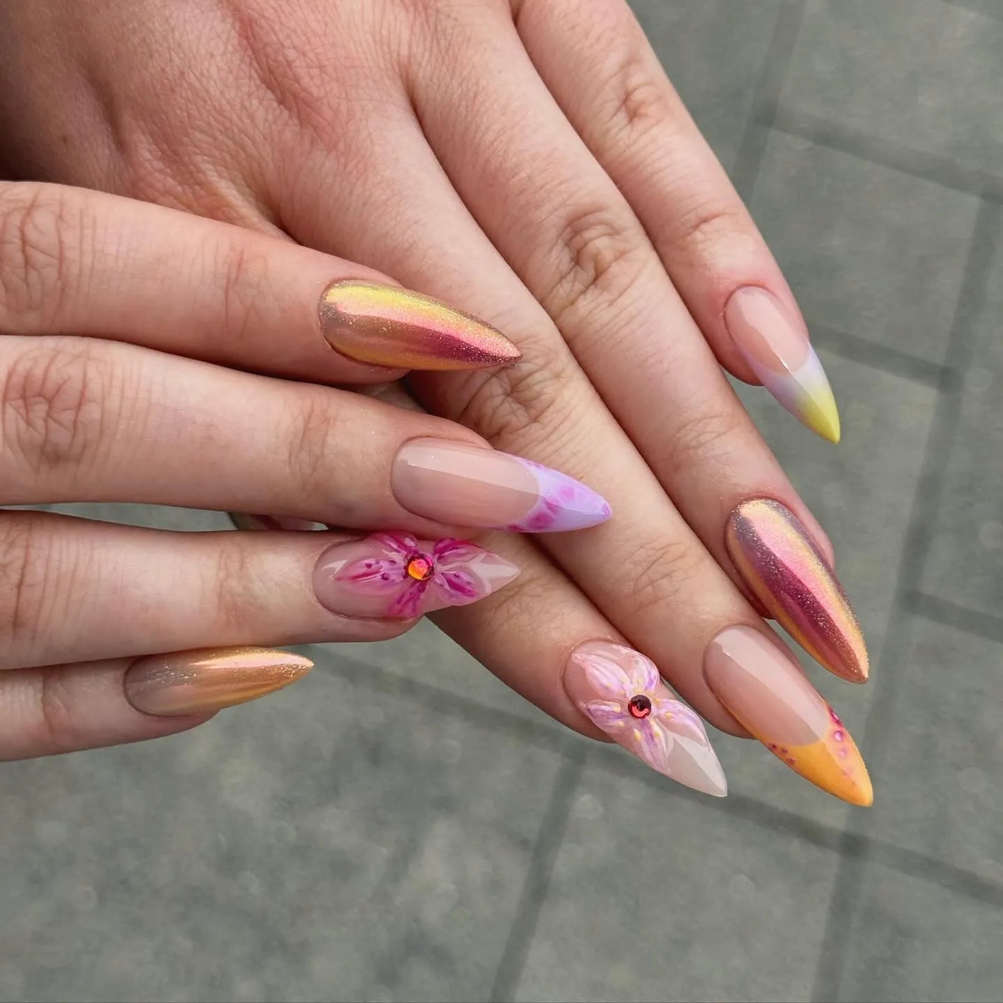 Hand with handmade iridescent sunset chrome pink 3D floral press-on nails, almond shape