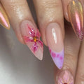 Handmade iridescent pink press-on nails with 3D floral accents and chrome shimmer.