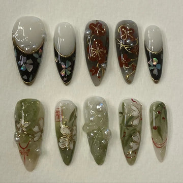 Handmade Japanese floral press-on nails with gold foil, pearl accents, and plum blossom designs.