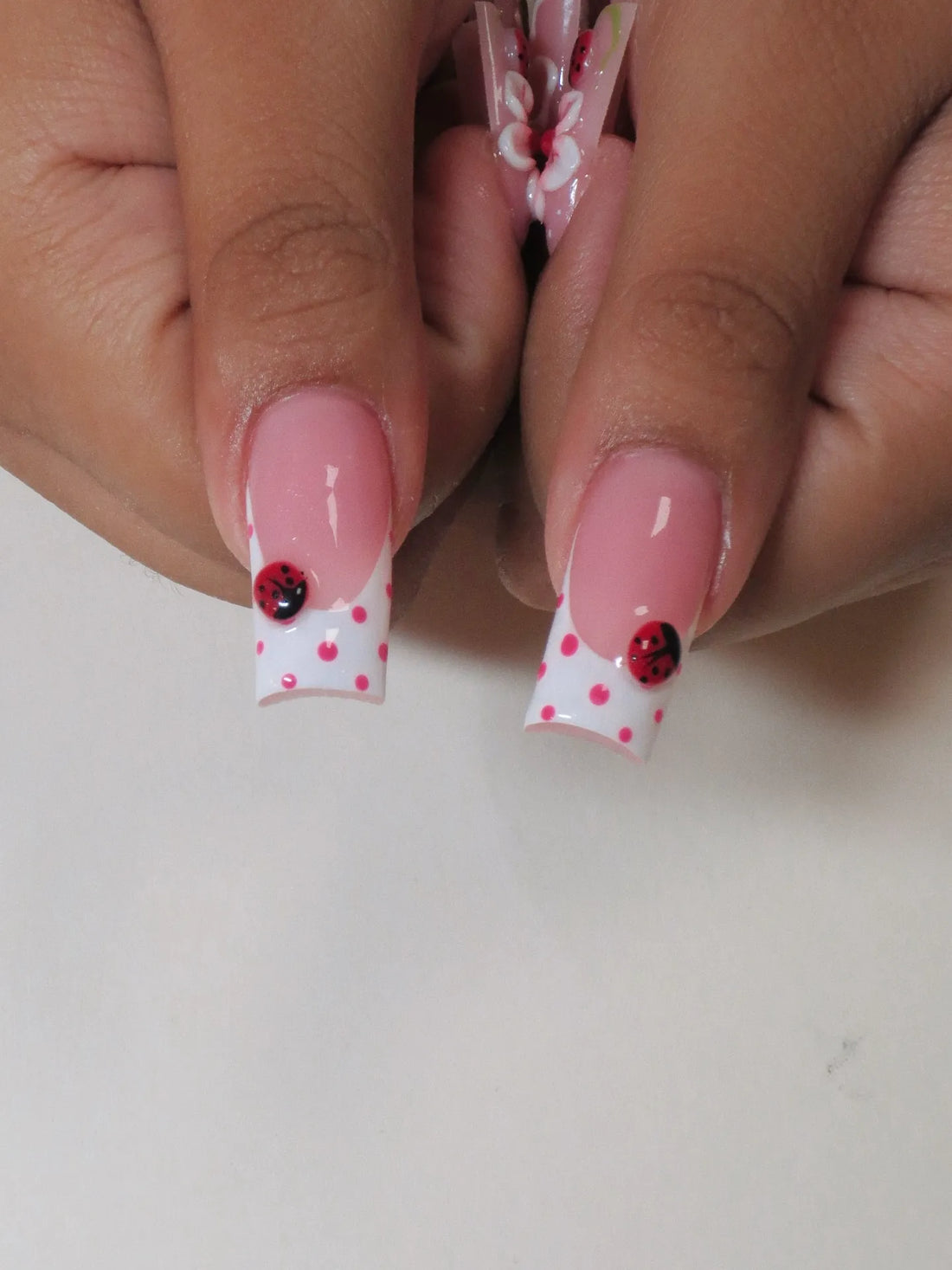 Handmade press-on nails with 3D ladybug, pink floral, white bow, and polka dot designs.