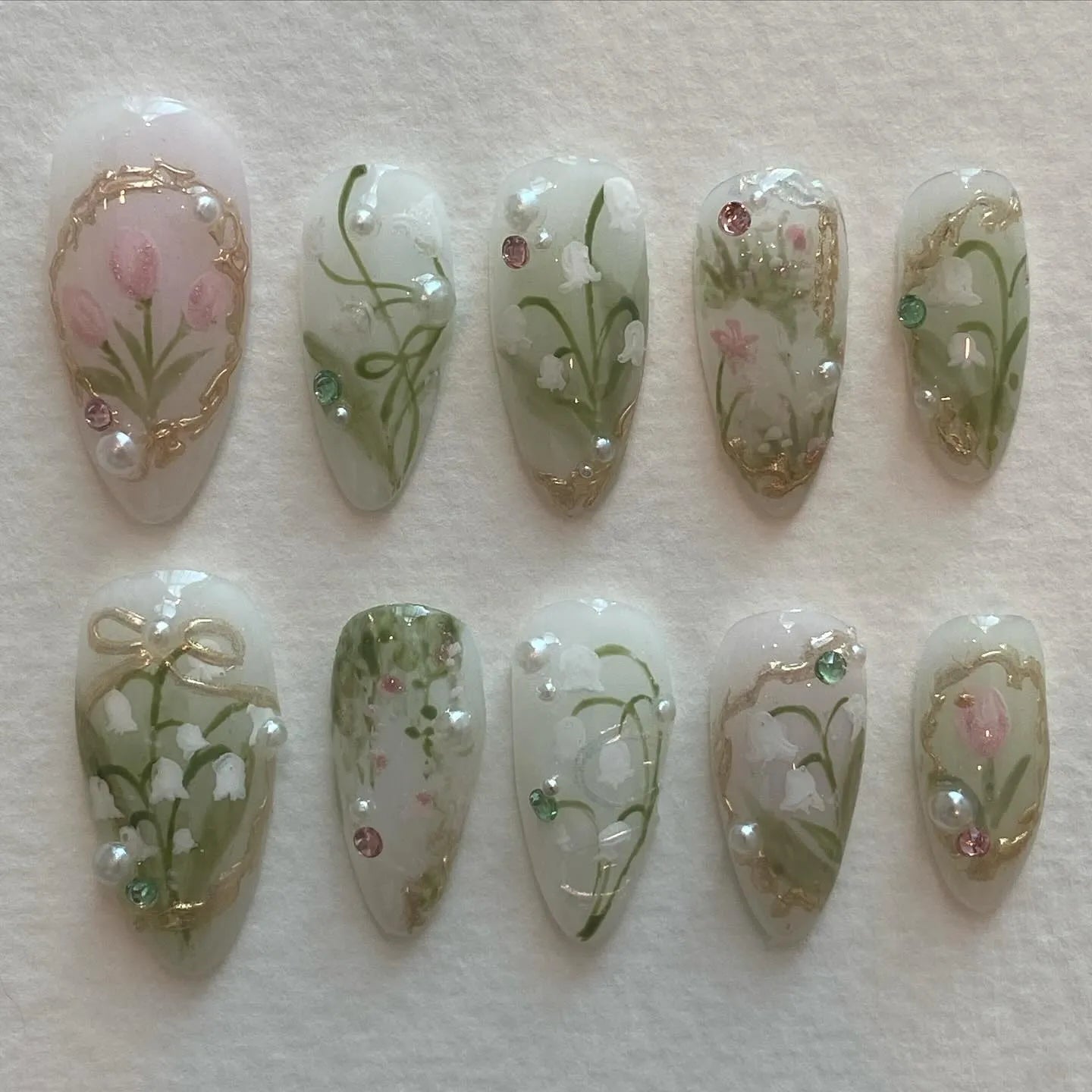 Handmade press-on nails with lily of the valley, tulip, pearl, and gold spring floral designs