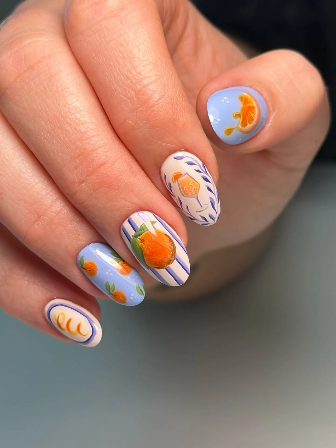 Handmade press-on nails with blue stripes and citrus fruit art, including lemons and oranges.
