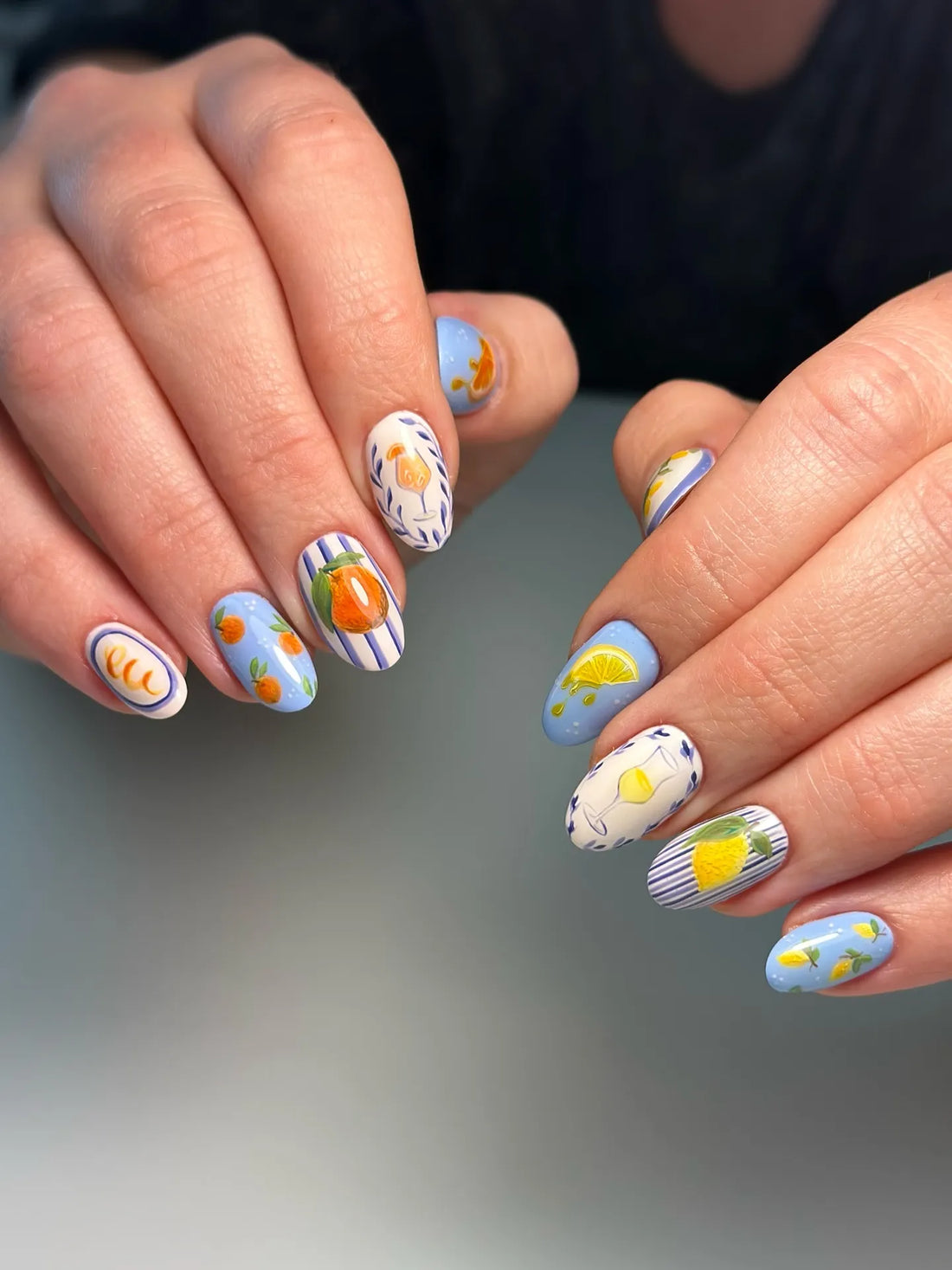 Handmade press-on nails with blue stripes and citrus fruit art, including lemons and oranges.