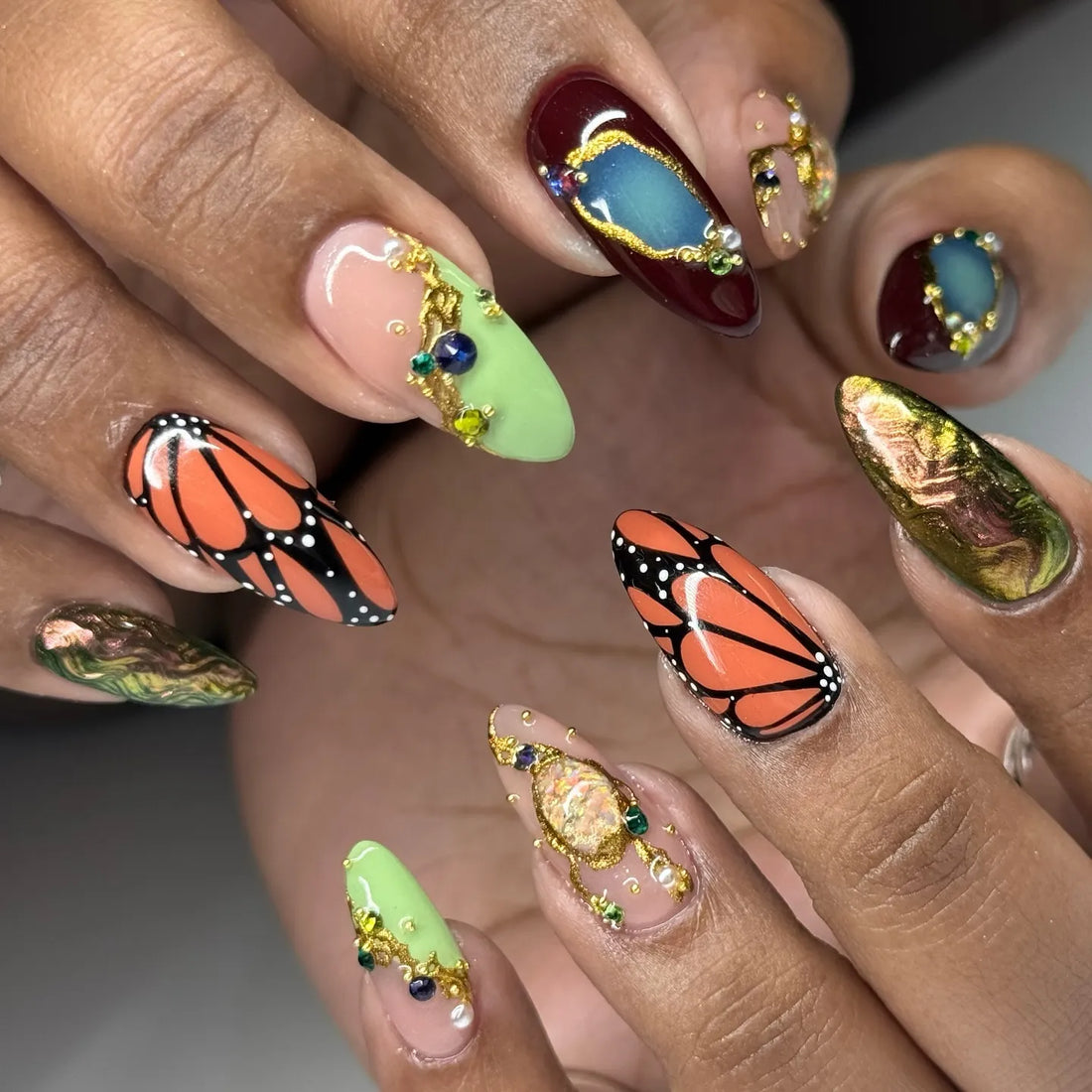 Handmade press-on nails with monarch butterfly, crystal jewel, and gold art details.