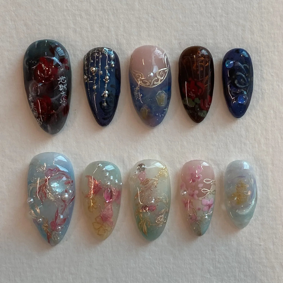 Handmade press-on nails with floral designs, pearls, crystals, and elegant blossoms.