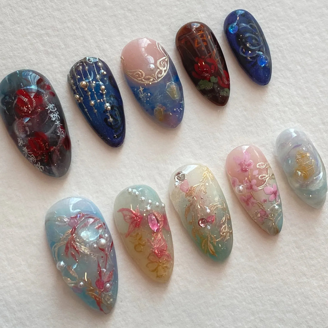 Handmade press-on nails with floral designs, pearls, crystals, and elegant blossoms.