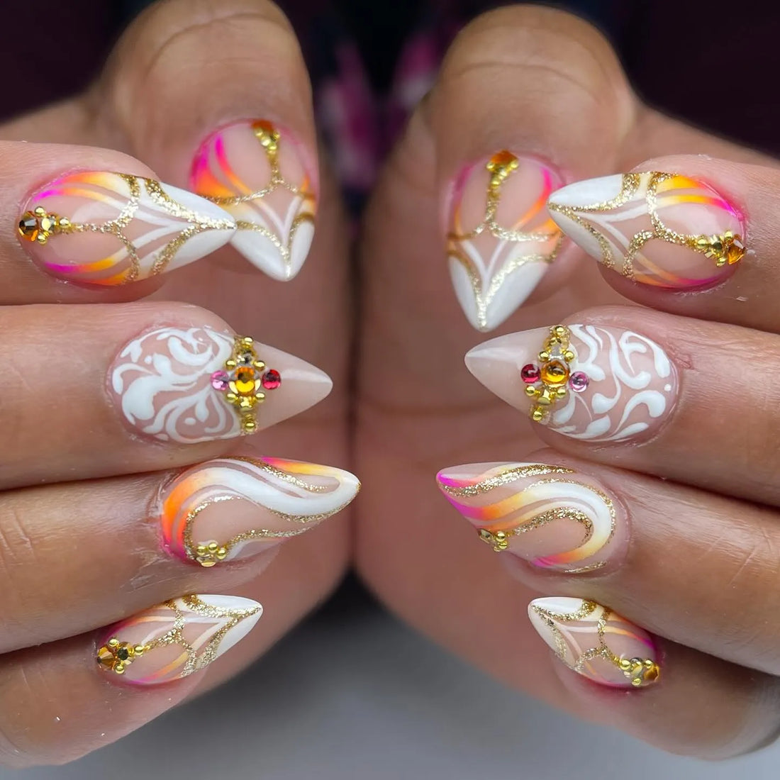 Handmade press-on nails with neon sunset colors, gold swirl accents, rhinestones, and white detailing