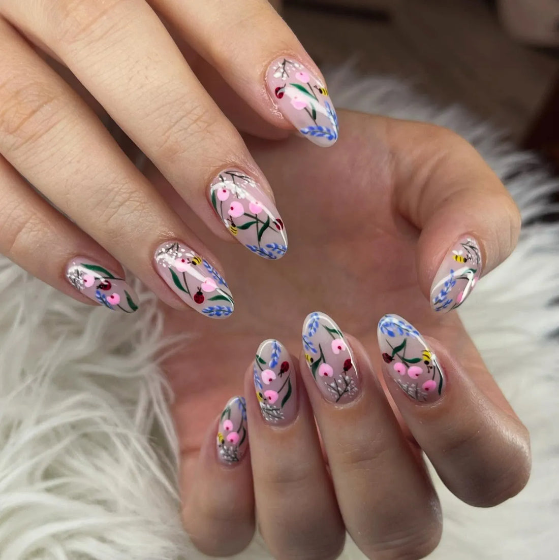 Handmade nude press-on nails with pink floral garden, bee, and ladybug nail art design