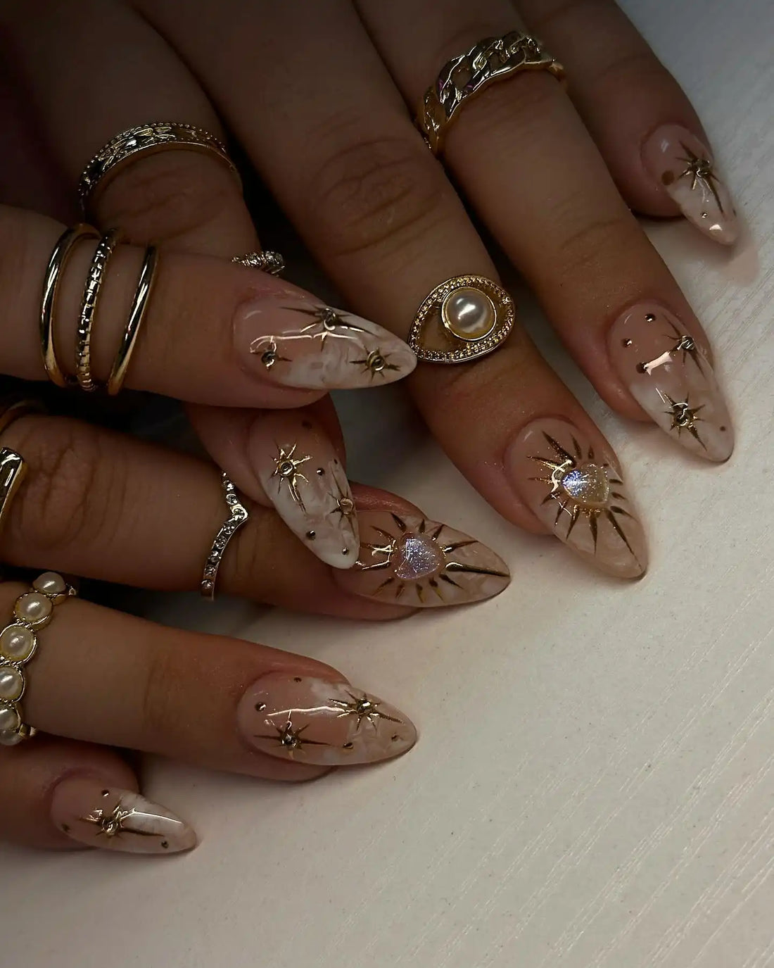 Handmade nude press-on nails with gold celestial heart charms and soft smoke art design