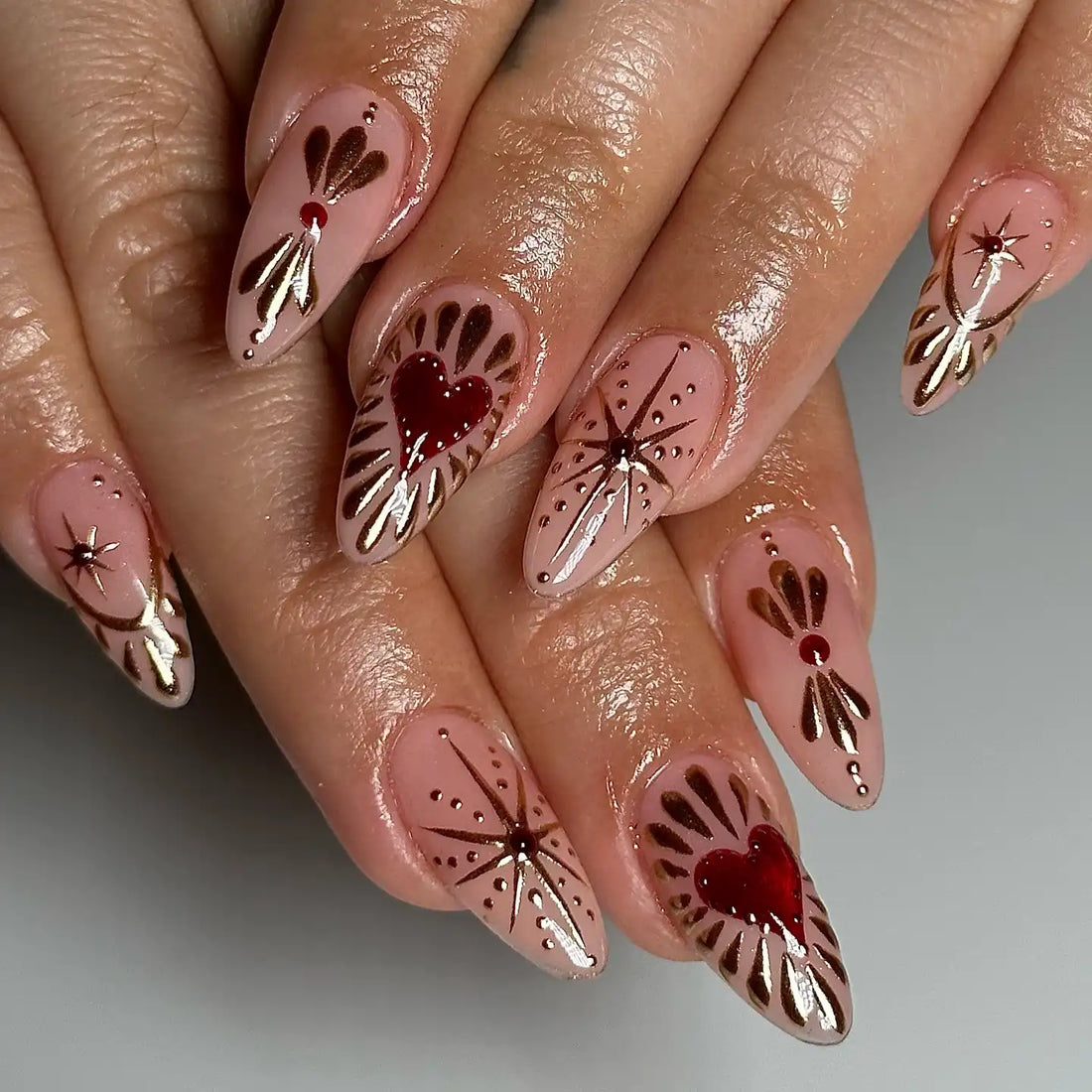 Handmade nude press-on nails with gold chrome starburst and red heart designs