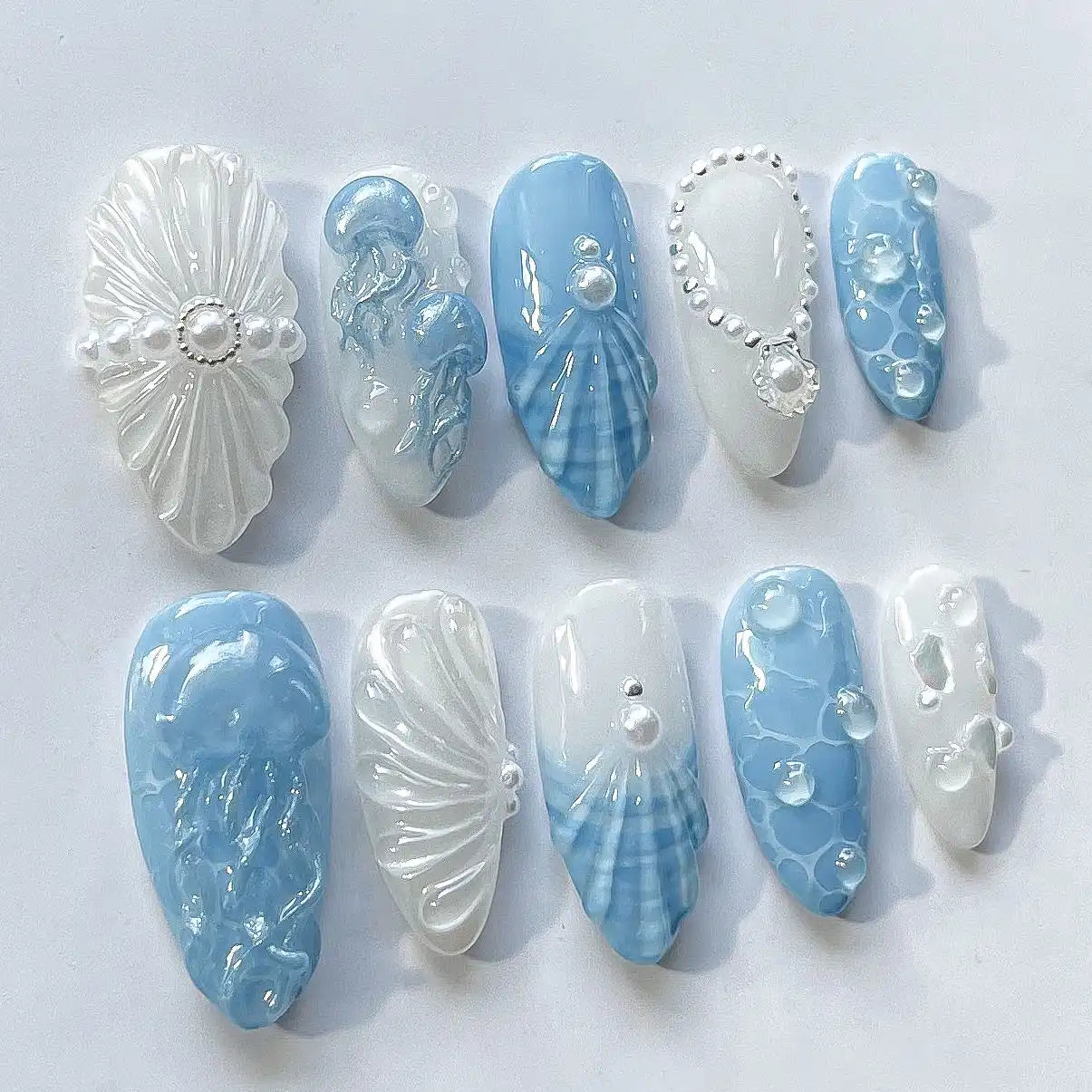 Handmade ocean blue and white press-on nails with 3D seashells, pearls, and jellyfish design