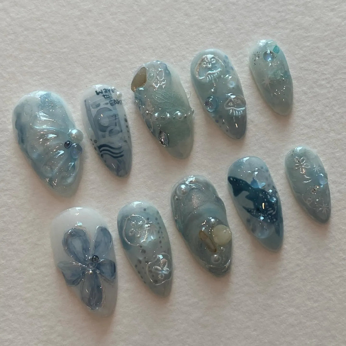 Handmade ocean blue press-on nails with whale, jellyfish, wave, pearl, and sea designs