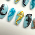 Handmade ocean-themed press-on nails with 3D shark, dolphin, and whale designs on blue base