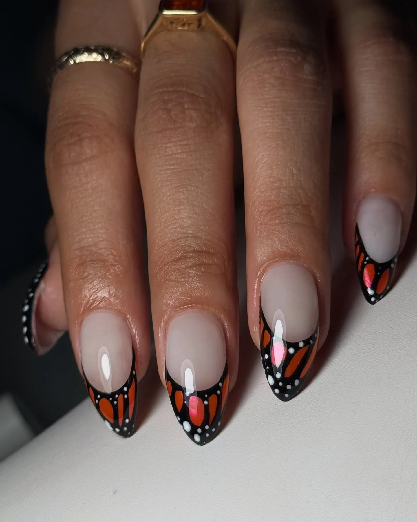 Hand with handmade press-on nails featuring orange monarch butterfly wing design