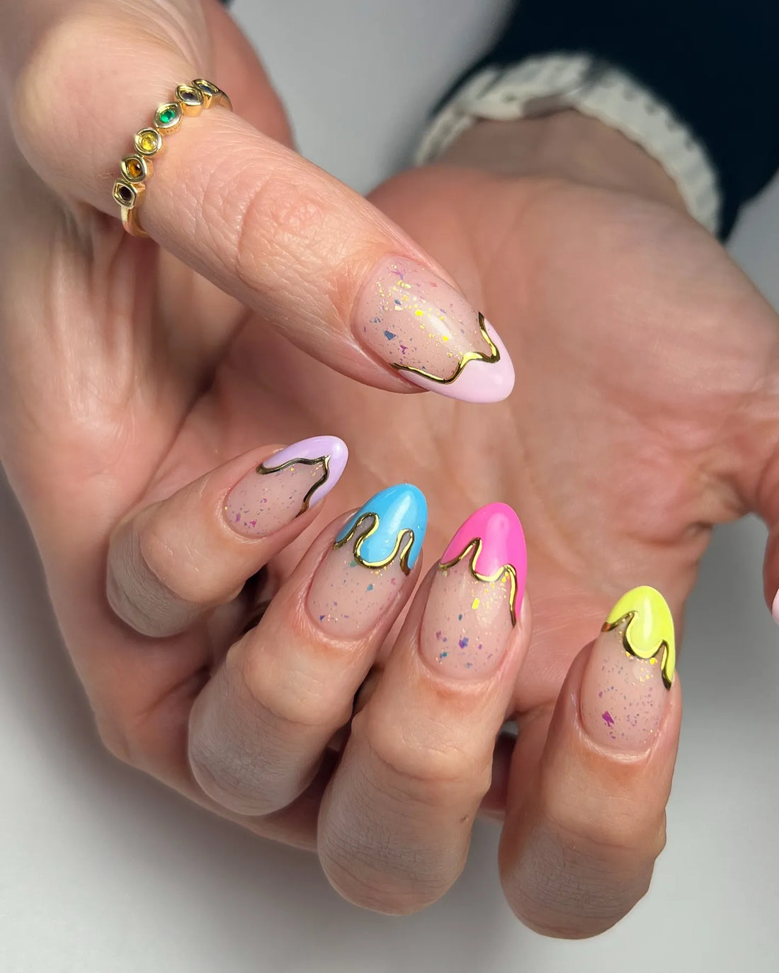 Handmade press-on nails with pastel neon drip design, gold accents, glitter flakes, almond shape