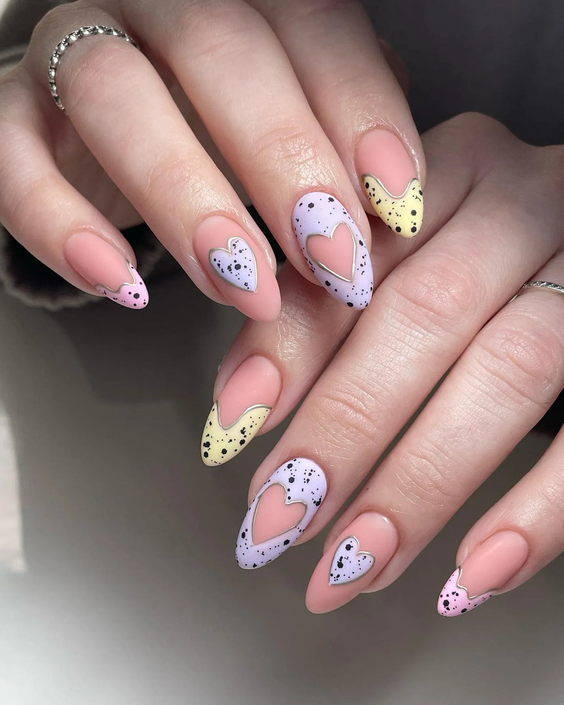 Handmade pastel press-on nails with speckled heart designs and silver outlines