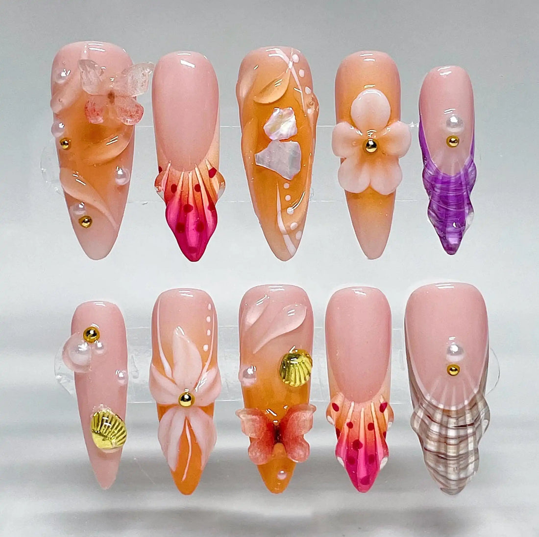 Handmade peach and gold press-on nails with flower, butterfly, shell, and pearl beach art designs