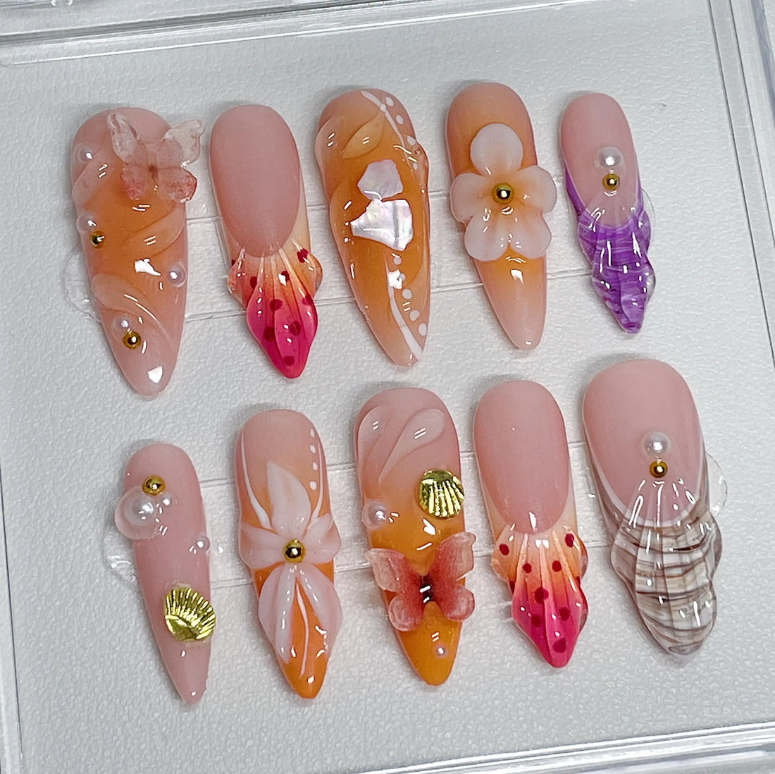 Handmade peach and gold press-on nails with flower, butterfly, shell, and pearl beach art designs
