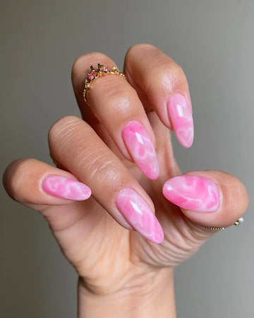 Hand with handmade pink marble jelly heart press-on nails in almond shape