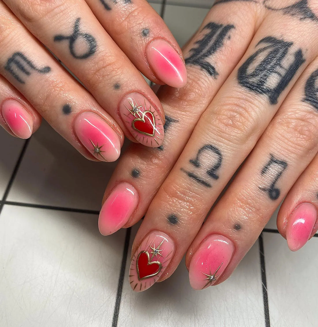 Handmade pink press-on nails with red heart, gold starburst, and mystical design accents