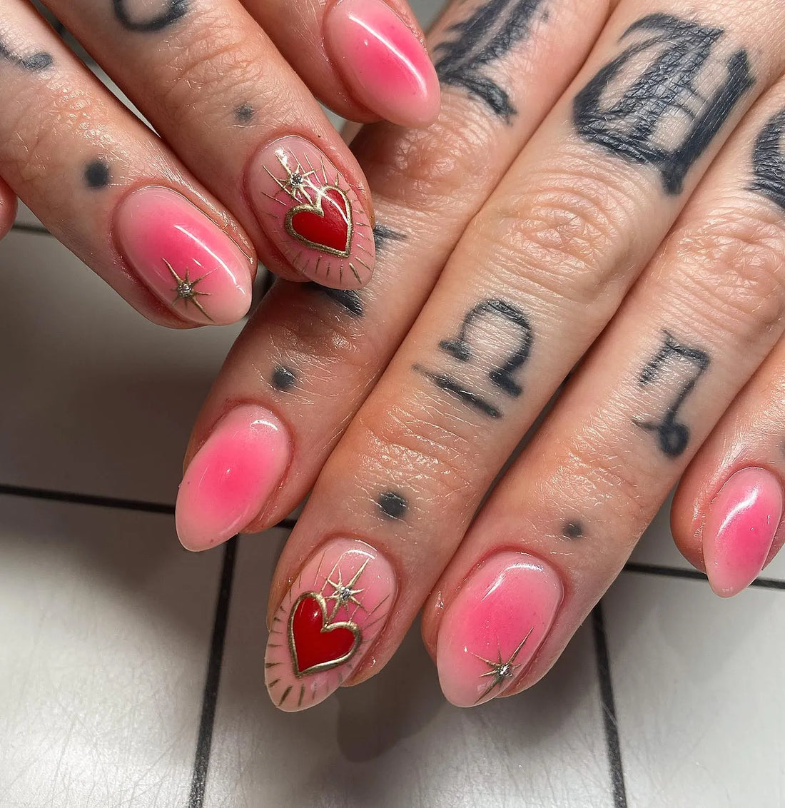 Handmade pink press-on nails with red heart, gold starburst, and mystical design accents