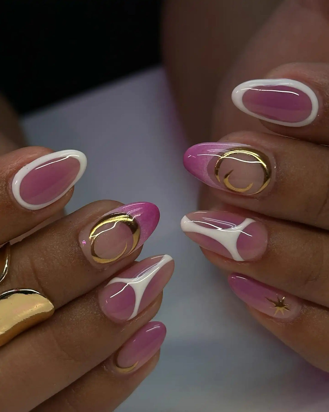 Handmade pink aura press-on nails with gold moon and star accents, white abstract tips.