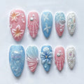 Handmade pink and blue press-on nails with seashell, jellyfish, floral, and mermaid designs.