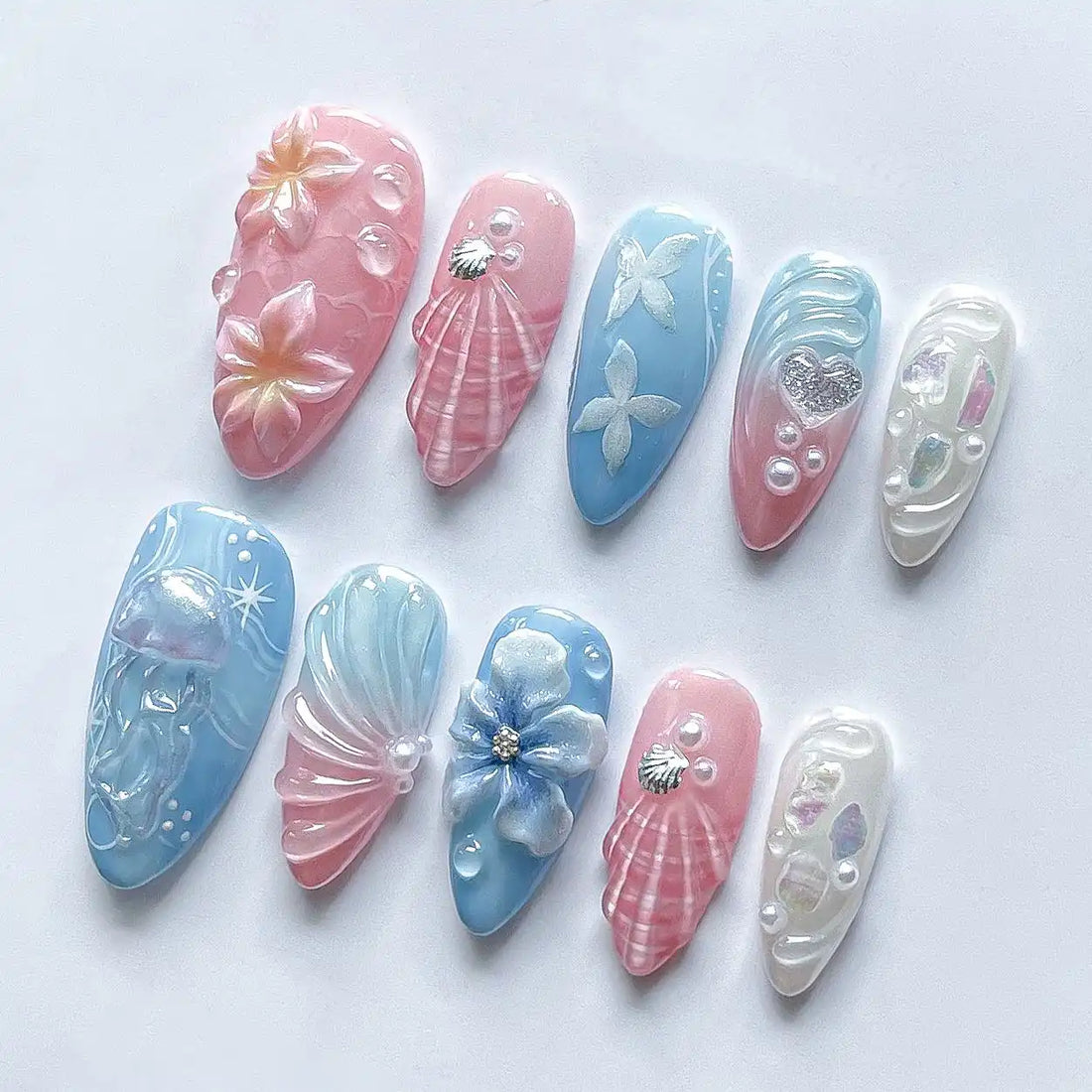Handmade pink and blue press-on nails with seashell, jellyfish, floral, and mermaid designs.