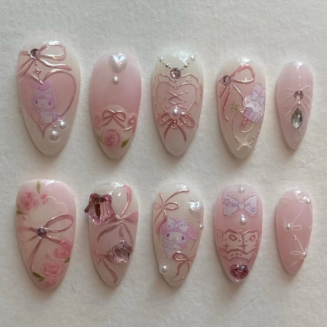 Handmade pink press-on nails with bows, roses, pearls, and cute character art, kawaii style