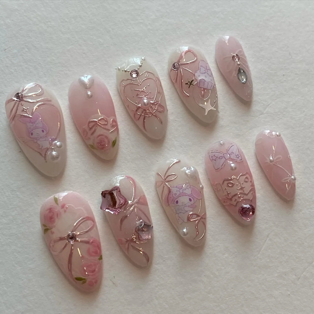 Handmade pink press-on nails with bows, roses, pearls, and cute character art, kawaii style