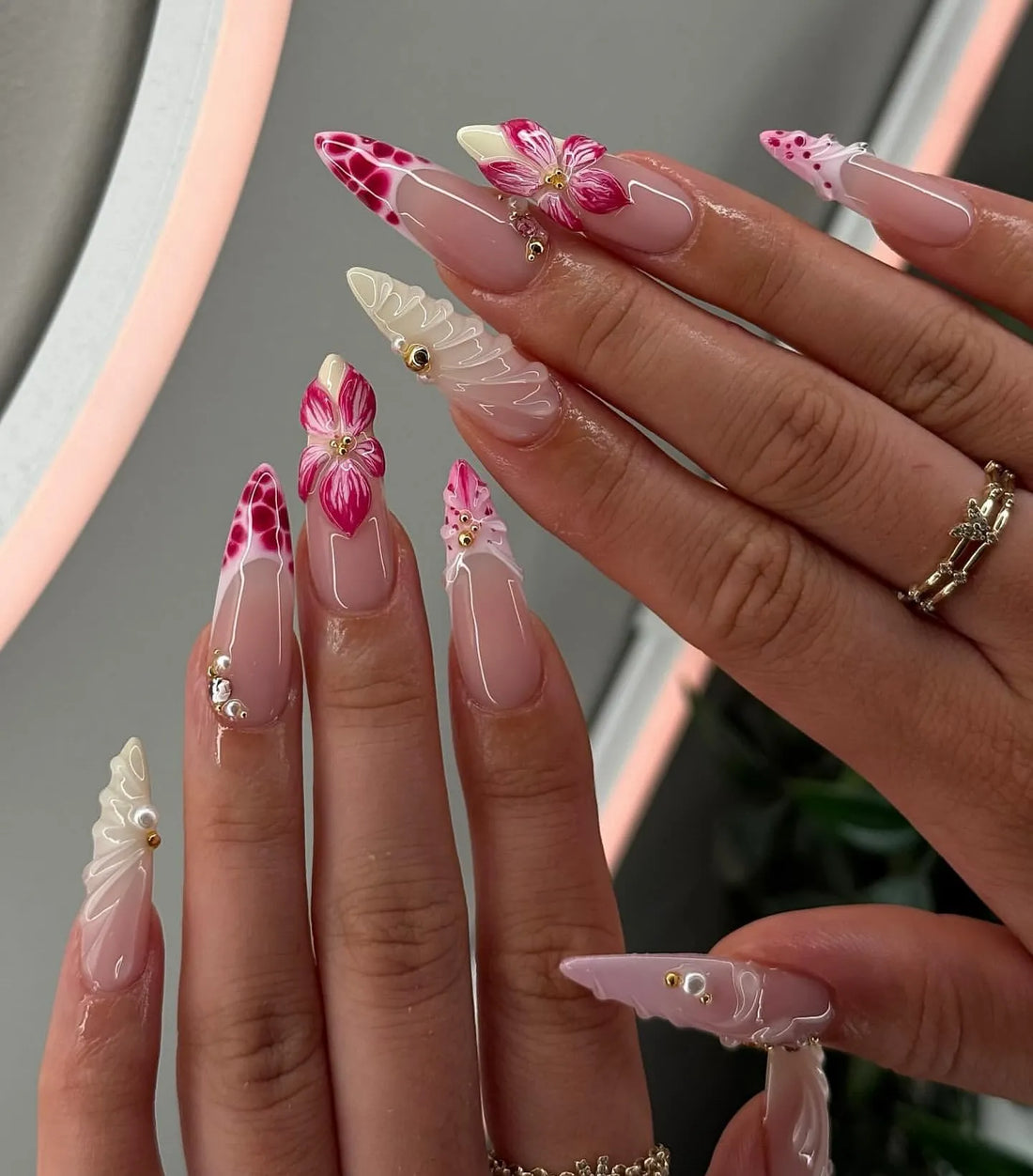 Hand with pink floral French swirl press-on nails, pearls, rhinestones, and elegant 3D accents.