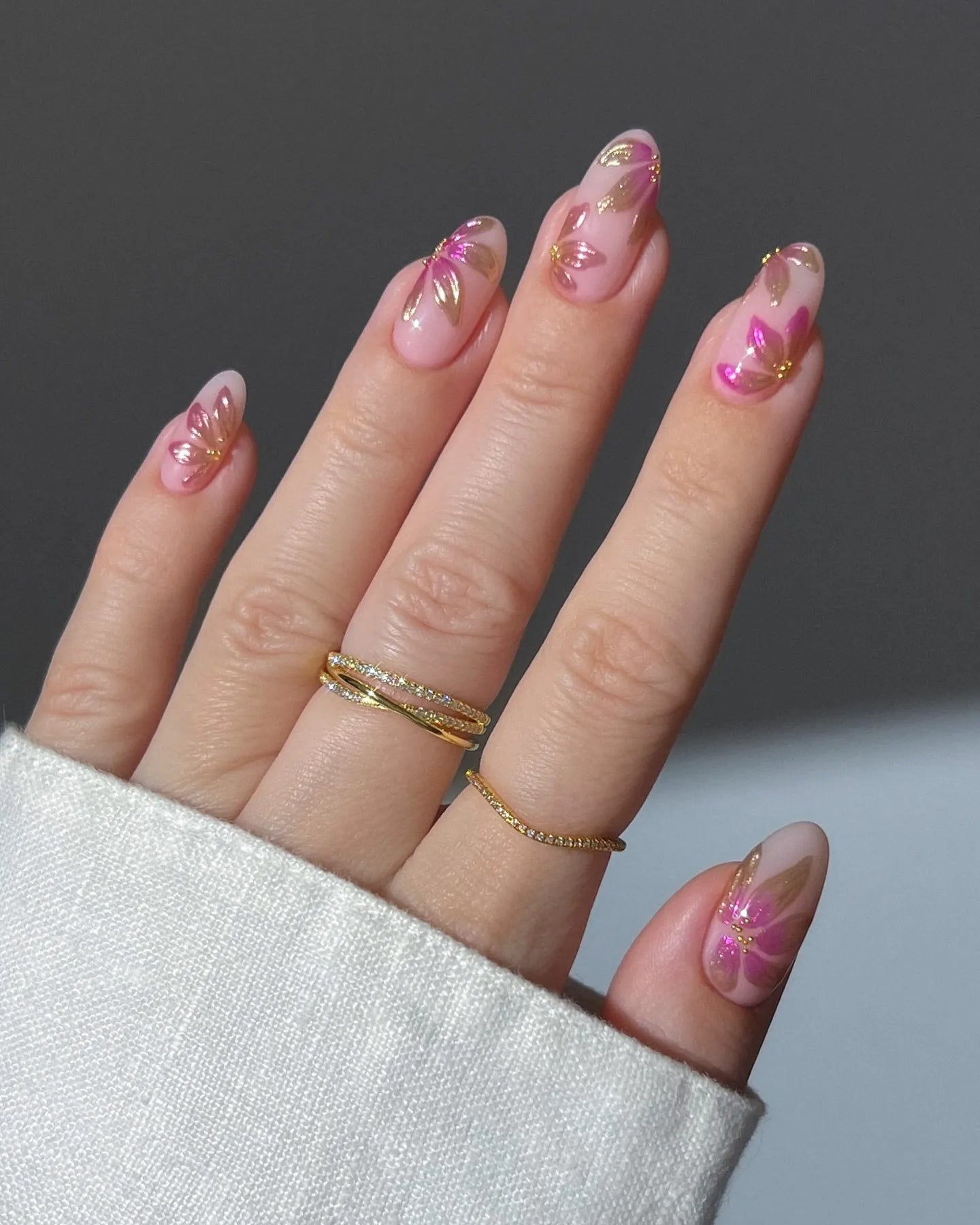 Hand with handmade pink press-on nails featuring gold foil floral leaf designs