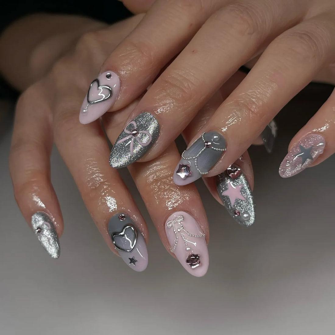 Handmade pink and grey press-on nails with chrome, glitter, 3D heart and star Y2K designs.