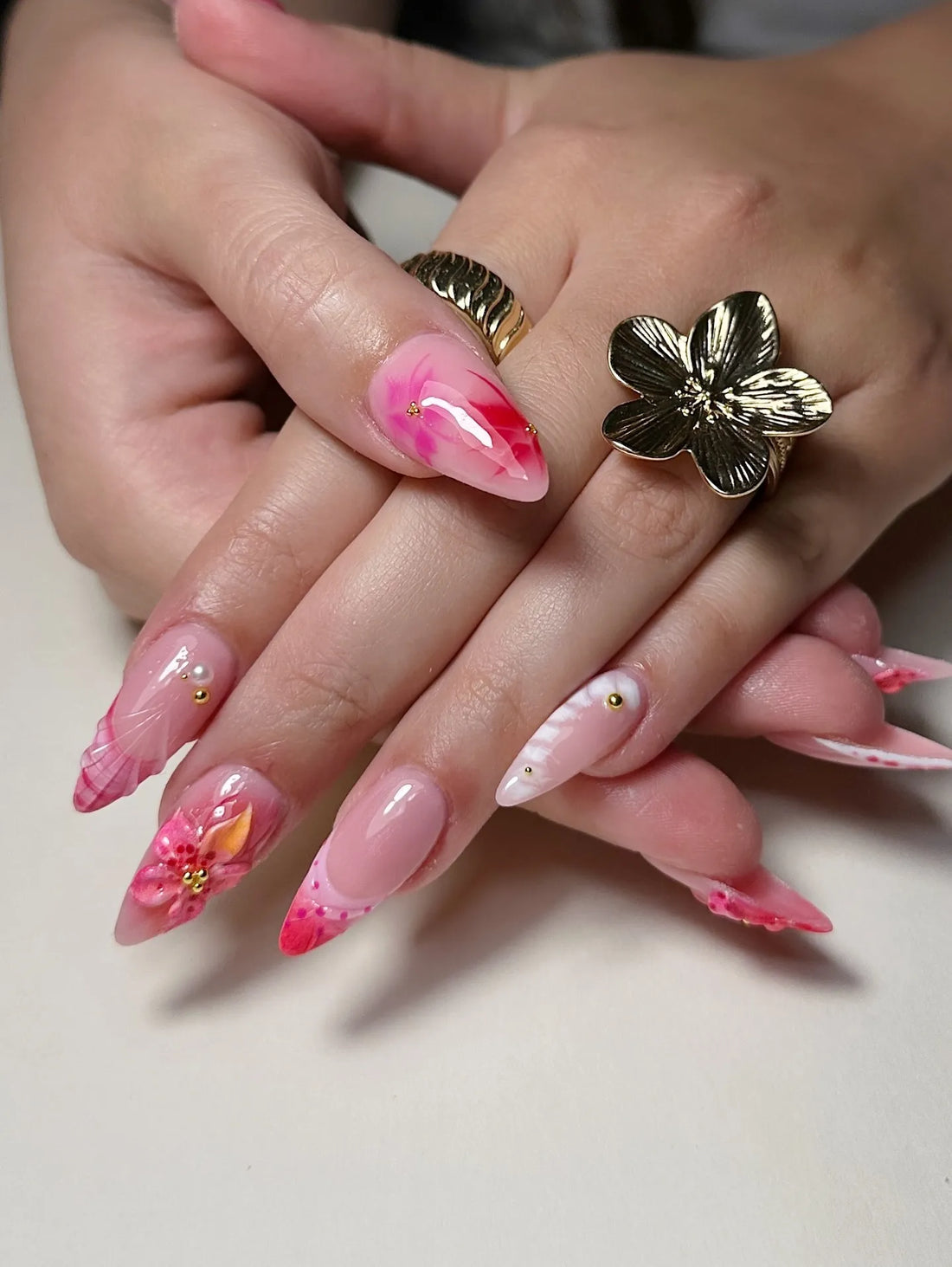 Hand with handmade pink 3D hibiscus floral, seashell, and French tip press-on nails