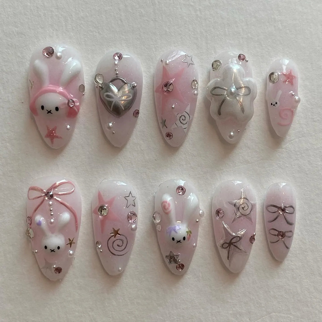Handmade pink kawaii press-on nails with bunny, star, bow, pearl, and crystal designs