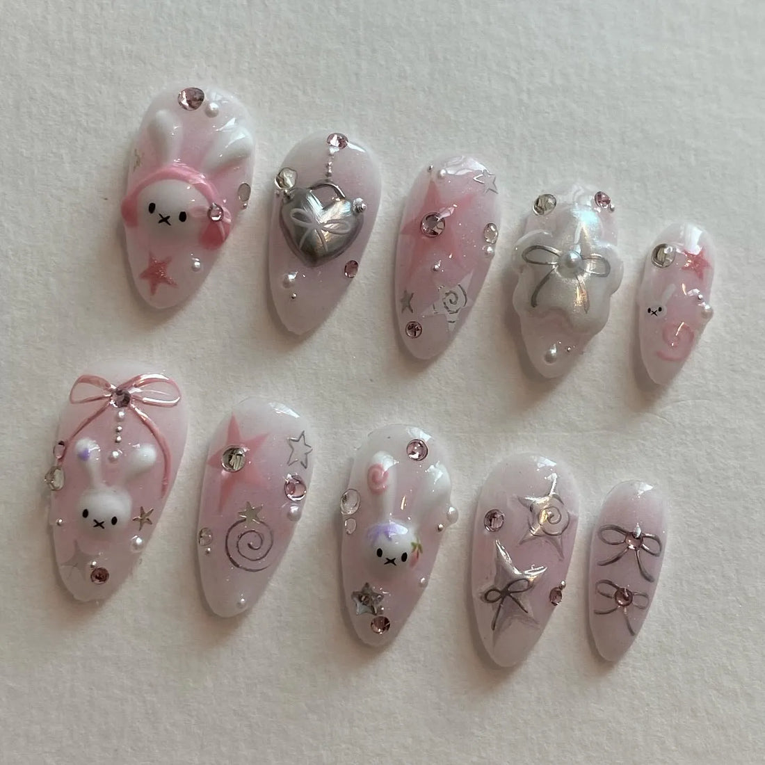 Handmade pink kawaii press-on nails with bunny, star, bow, pearl, and crystal designs
