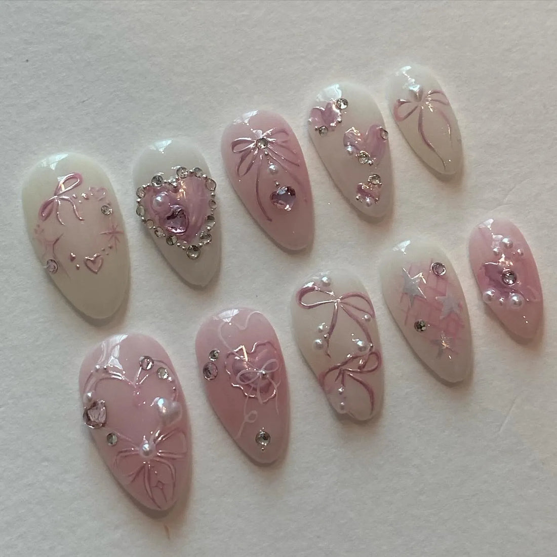 Handmade pink heart charm press-on nails with bow, crystal, and pearl accents, reusable set