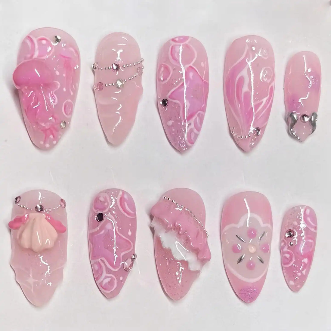 Handmade pink press-on nails with jellyfish, seashell, rhinestone, and fairycore accents.