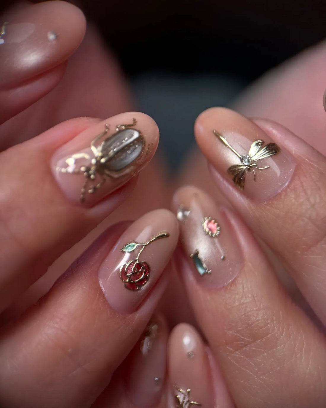 Handmade pink nude press-on nails with gold insect, dragonfly, rose, and gemstone accents