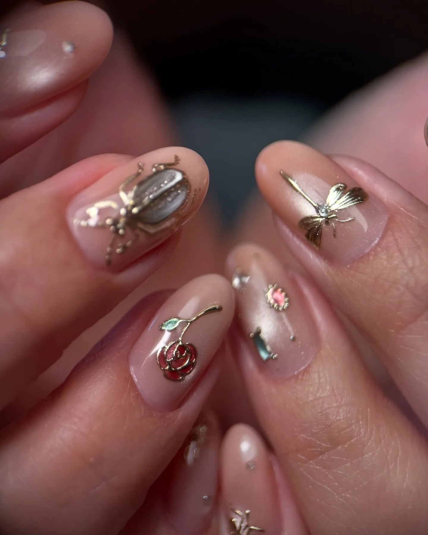 Handmade pink nude press-on nails with gold insect, dragonfly, rose, and gemstone accents