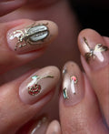 Handmade pink nude press-on nails with gold bug, butterfly, rose, and gemstone accents