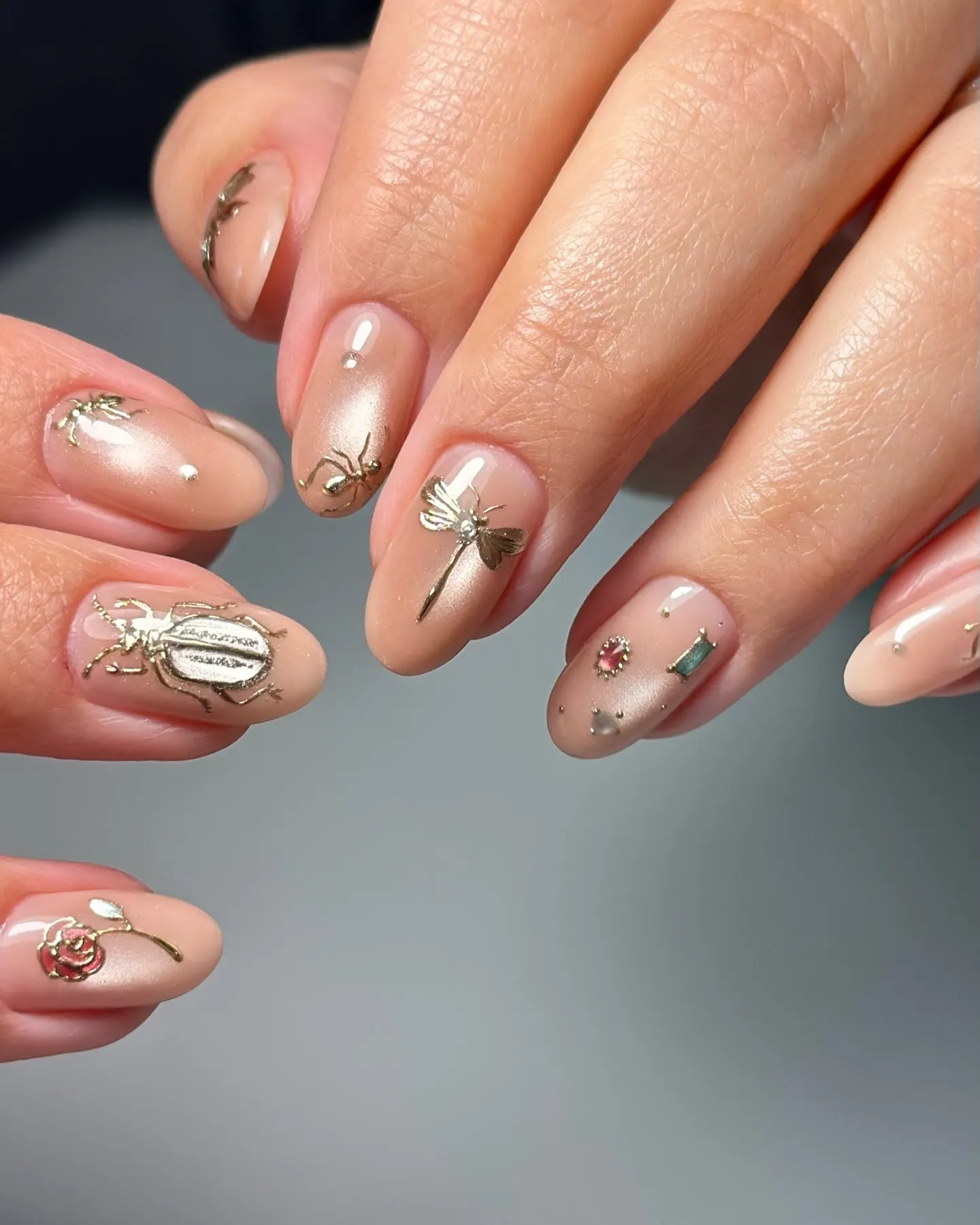 Handmade pink nude press-on nails with gold insect and gem decals, chic and elegant design.