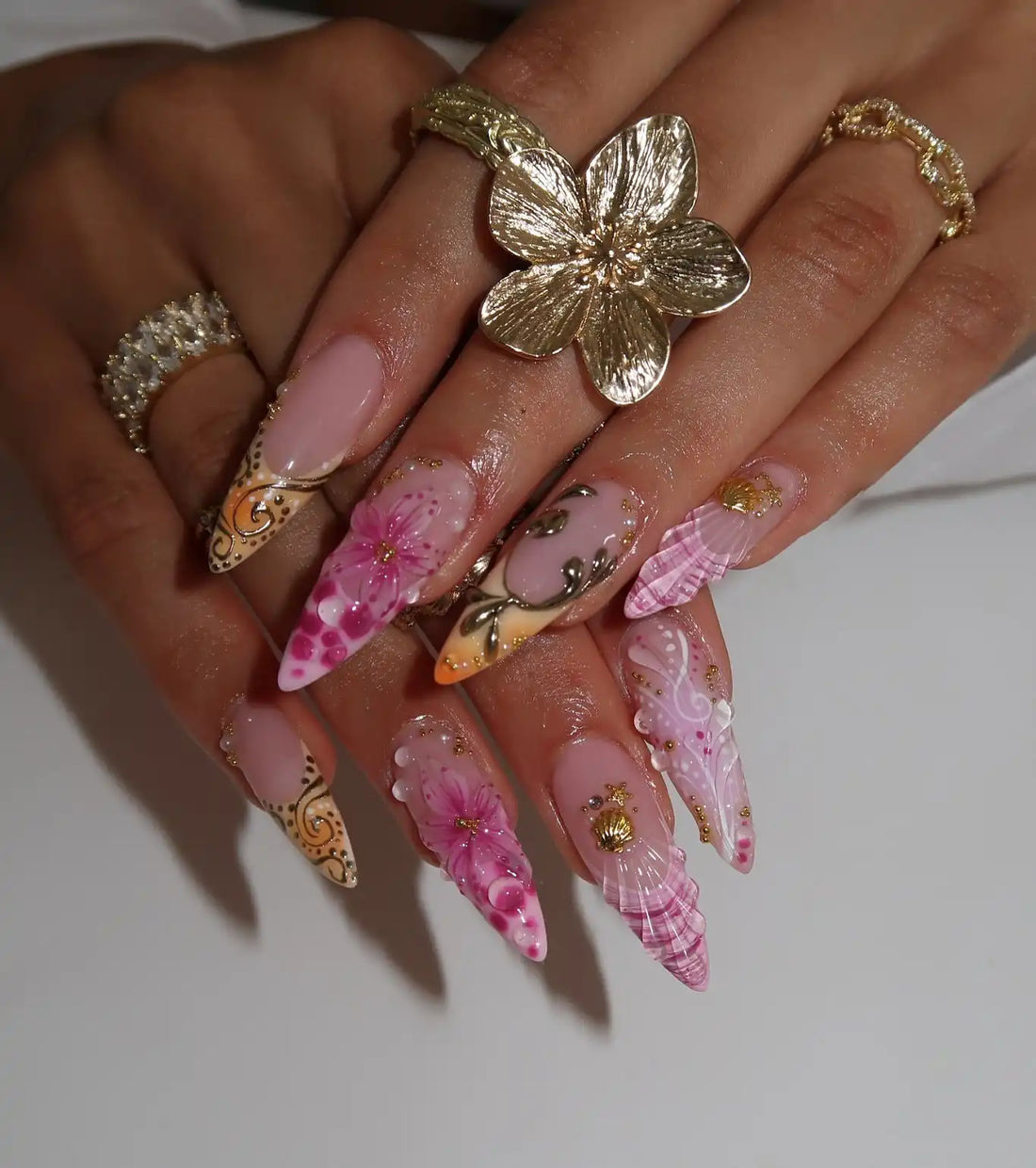 Handmade pink ombre press-on nails with gold seashell, floral, and water drop designs.