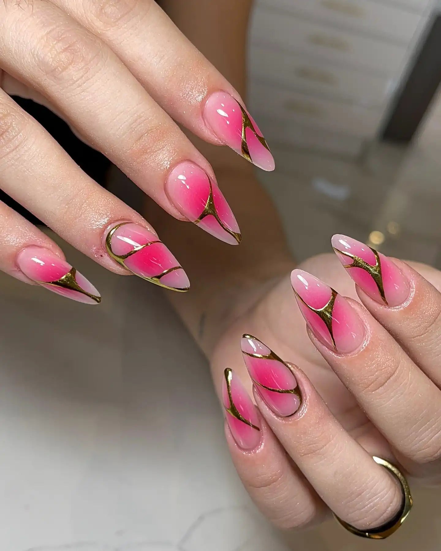 Handmade pink ombre press-on nails with glossy finish and gold-lined edgy design