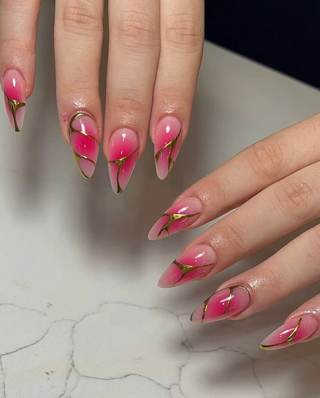 Handmade pink ombre press-on nails with glossy finish and gold-lined edgy design