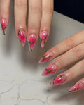 Hand with almond-shaped pink ombre press-on nails, gold lined edges, glossy finish
