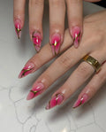 Hand with glossy pink ombre press-on nails featuring gold-lined edgy designs