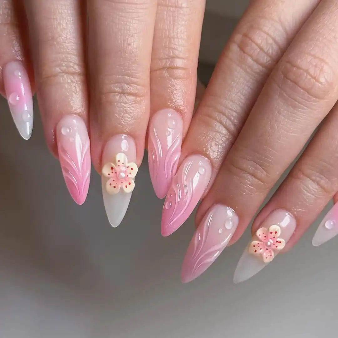 Handmade pink ombre press-on nails with yellow 3D flower and pearl accents, almond shape