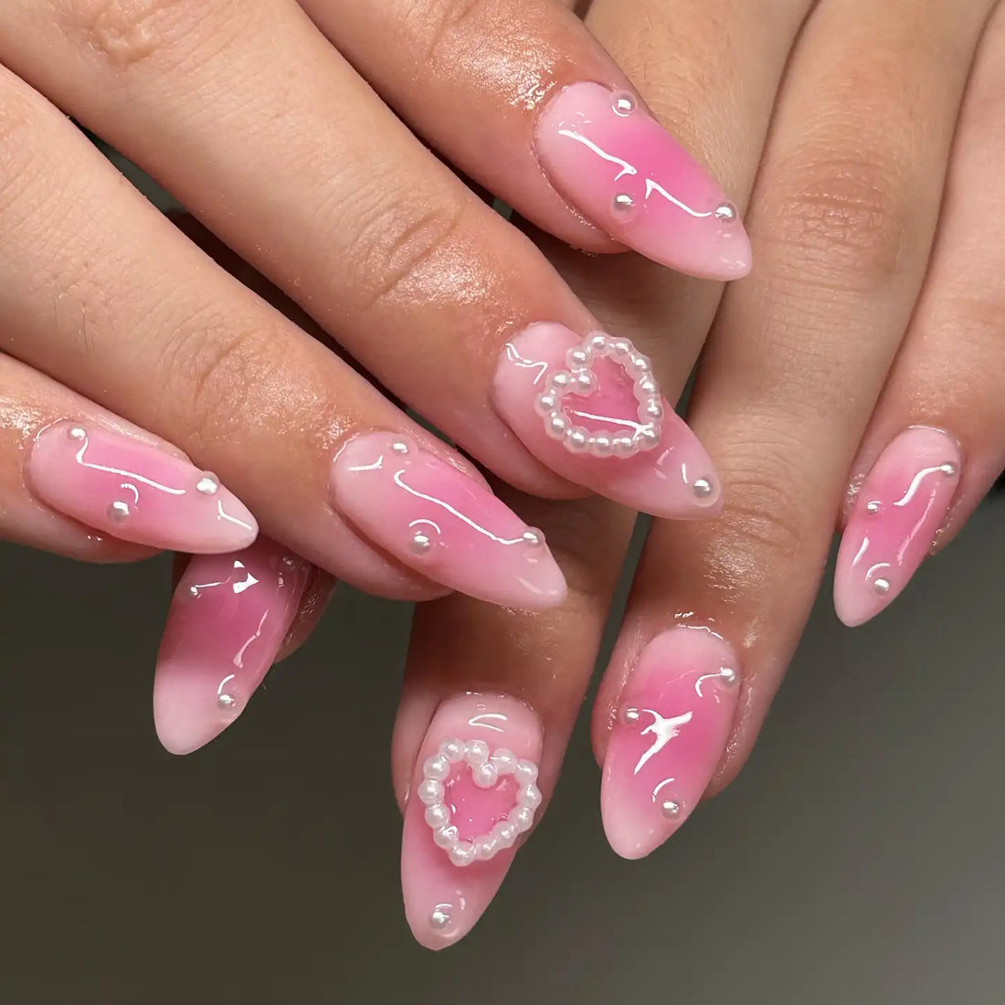 Handmade pink press-on nails with glossy finish, pearl heart accents, and romantic design
